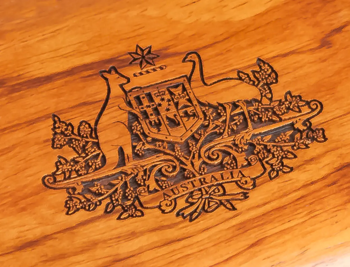 Australian Government coat of arms engraved into solid timber, shown in close-up